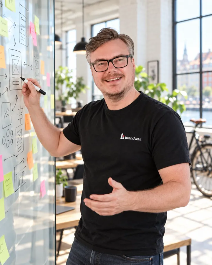 Janus, founder of Brandwall, sketching screens on a glass wall full of sticky notes